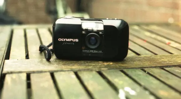 Olympus mju-1 camera, a classic choice for the best film for Olympus Stylus, rests on a weathered wooden surface.