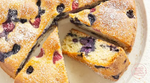 Saftiger, veganer Kuchen mit Blaubeeren und Himbeeren, bestäubt mit Puderzucker. Ein Genuss für alle!