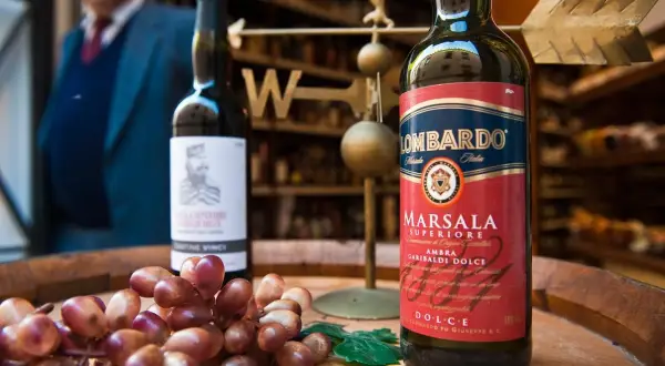 Słodkie wino deserowe Marsala Lombardo, obok kiść winogron.