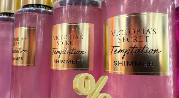 Różowe mgiełki Victoria's Secret Temptation Shimmer z złotymi etykietami i złotym symbolem procentu.
