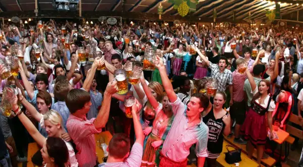 Menschen jubeln und stoßen mit Bierkrügen an auf dem Volksfest Freising.
