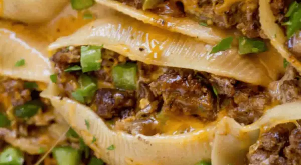 Close-up of cheesy, savory philly shell pasta stuffed with seasoned ground beef and green peppers, a delicious comfort food.
