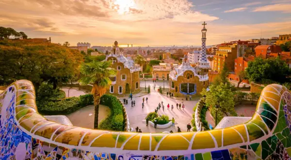 Park Güell w Barcelonie, jednym z największych miast Hiszpanii, zachwyca mozaikową ławką i bajkowymi budynkami o zachodzie słońca.