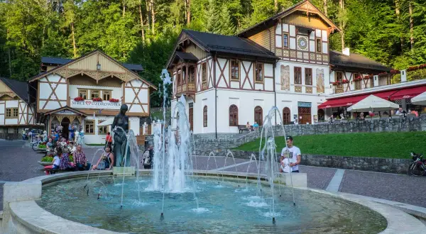 Fontanna i urokliwe budynki tworzą piękne **Szczawnica atrakcje**. Ludzie odpoczywają, ciesząc się atmosferą uzdrowiska.