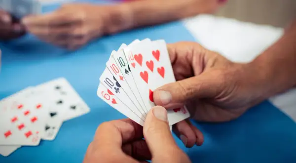 Hände halten Spielkarten, ein Spiel zur Förderung der kognitiven Fähigkeiten bei Demenz.