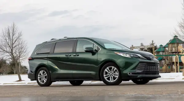 Zielona Toyota Sienna zaparkowana obok placu zabaw.