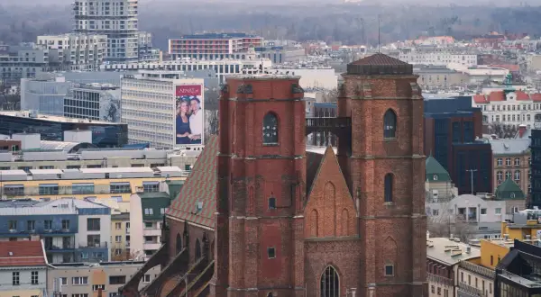 Widok na ceglany kościół garnizonowy we Wrocławiu, otoczony nowoczesną zabudową miejską.