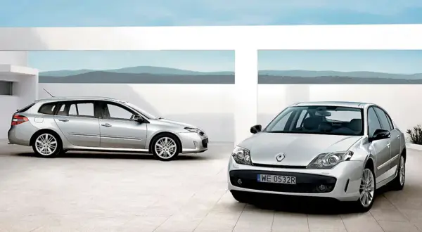 Dwa srebrne Renault Laguna 3 2.0 dCi: kombi i sedan, stojące na nowoczesnym placu z widokiem na góry.
