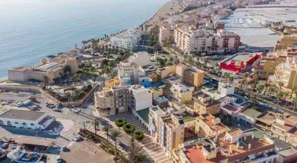 Vista aérea del **centro de Roquetas de Mar**, con el castillo, la playa, edificios residenciales y el mar Mediterráneo.
