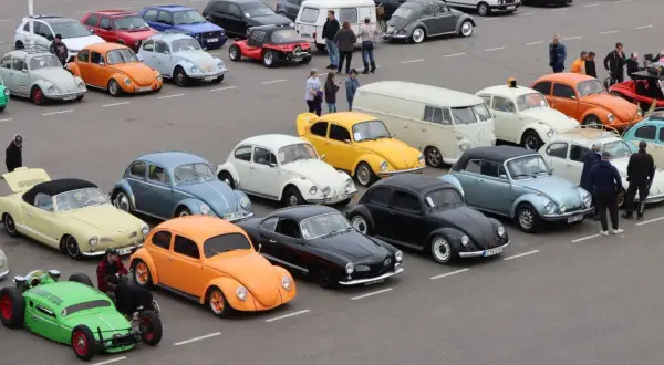En samling 90 tals bilar, mestadels bubblor och några skåpbilar, uppradade på en parkering.