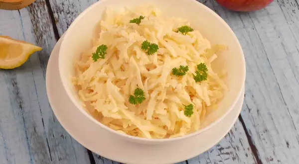 Pyszna surówka z selera i jabłka, udekorowana natką pietruszki, na drewnianym blacie.