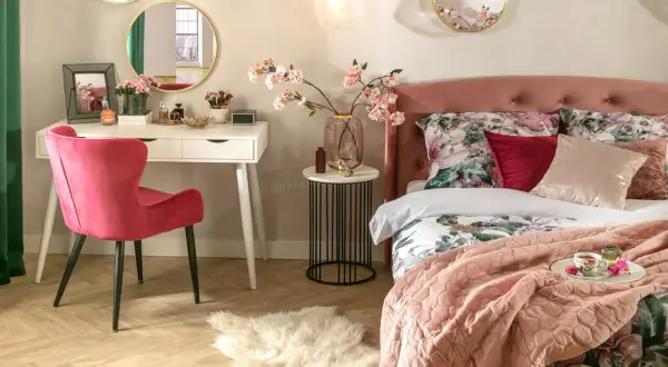 Elegancka toaletka w sypialni z różowym krzesłem, lustrami i kwitnącymi gałązkami wiśni.