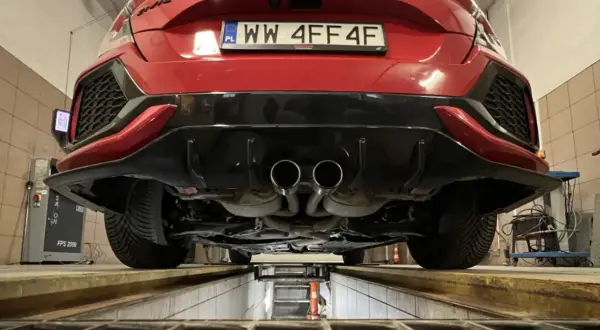 Czerwone auto na podnośniku, podwójny wydech. Zastanawiasz się, ile kosztuje przegląd auta 2026?