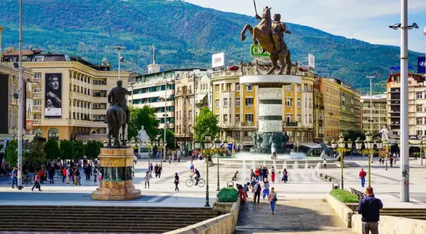 Pomnik wojownika na koniu na placu w Skopje, Macedonia Północna, z górami w tle.