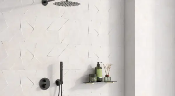 Ducha moderna con azulejo rectificado de diseño geométrico en blanco. Incluye rociador, grifería negra y estante con productos de baño.