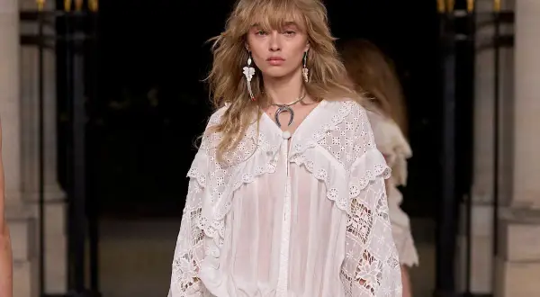 Modelo luce un vestido blanco con encaje, estilo boho, con pendientes largos y collar plateado.