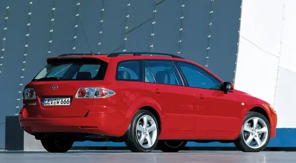 Czerwona Mazda 6 GG kombi stoi na tle nowoczesnego budynku.