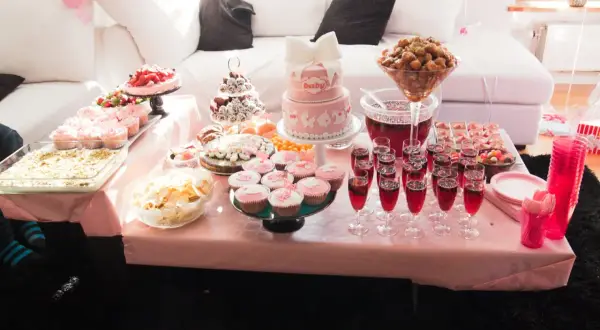 Ett rosa buffébord med många rosa kakor och cupcakes, perfekt för en babyshower.