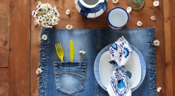 Tovagliette americane fai da te in denim con tasca porta posate, decorate con margherite e un servizio da tavola blu e bianco.