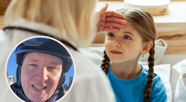 Lekarz bada gorączkującą dziewczynkę, sprawdzając jej czoło. W tle widać mężczyznę w kasku. Objawy adenowirusa mogą być różne.