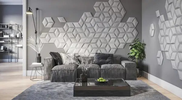 Nowoczesna dekoracja co na ścianę w pokoju: geometryczne panele 3D tworzą efektowny wzór nad szarą sofą.