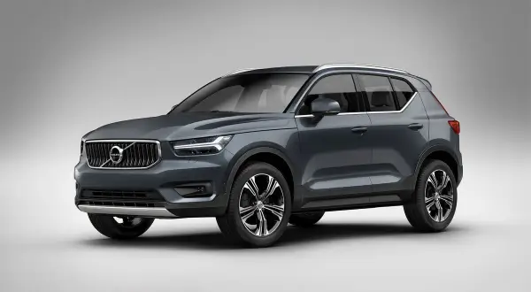Elegancki, ciemnoszary Volvo XC40 prezentuje się na tle jasnej ściany, gotowy na miejskie wyzwania.