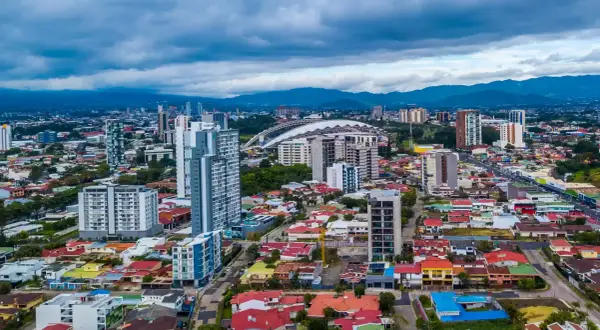 Vy över San José, Costa Rica, med moderna skyskrapor och färgglada hus under en molnig himmel.