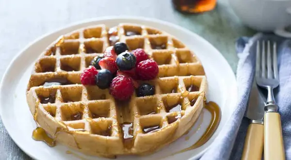 Waffle dorato con sciroppo d'acero e frutti di bosco, perfetto per una ricetta waffle golosa.