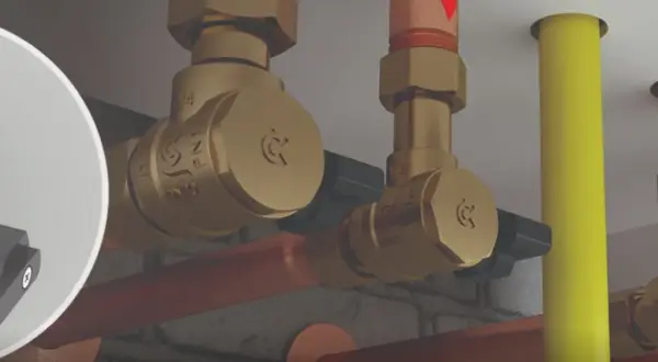 Zobacz, jak działa zawór zwrotny. Mosiężne elementy instalacji hydraulicznej, miedziane rury i żółty przewód.