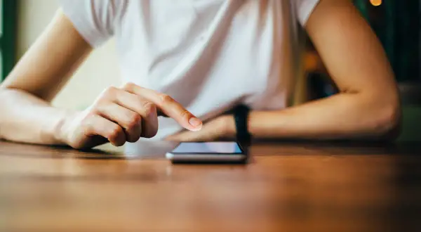 Dłoń dotyka ekranu telefonu, szukając informacji, jak zresetować telefon Redmi.