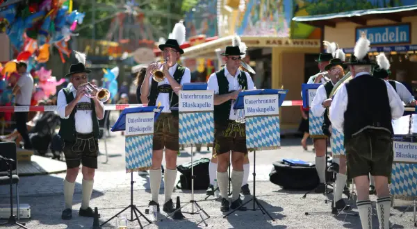 Blaskapelle spielt beim Taufkirchen Volksfest. Musiker in Tracht mit Hüten und Federn spielen Trompeten und Hörner.