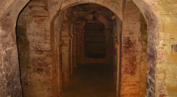 Corridoio sotterraneo con archi in mattoni e pietra a Monsampolo del Tronto, evocando misteri antichi.