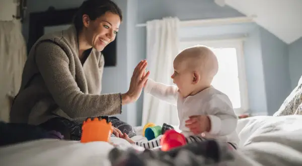 Mama i dziecko dają sobie piątkę. To świetna zabawa i nauka dla 10-miesięcznego dziecka, rozwijająca koordynację i więź.