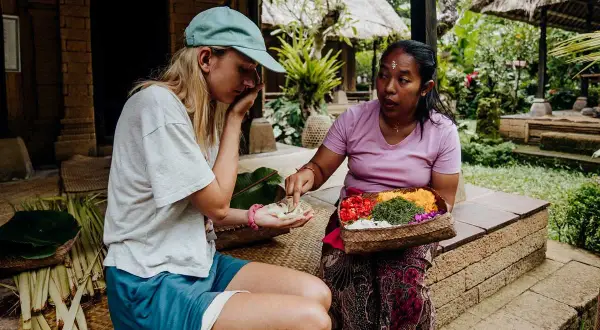 Une touriste apprend à faire des offrandes avec sa guide à Bali.