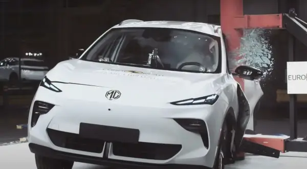 Białe chinskie auto MG po teście zderzeniowym Euro NCAP, z rozbitą szybą i uszkodzonymi elementami.