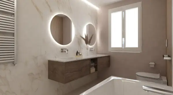 Bagni eleganti con pareti in marmo, doppio lavabo con specchi rotondi illuminati, mobile sospeso in legno e vasca da bagno.