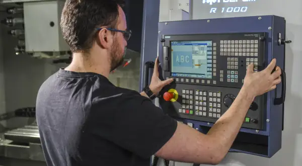 Operator CNC przy panelu sterowania maszyny. Zastanawiasz się, ile zarabia operator CNC w Niemczech?