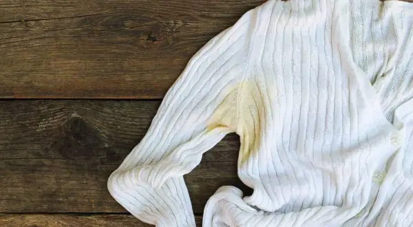 Maglione bianco con evidenti macchie gialle sotto l'ascella, un problema comune per chi cerca come togliere macchie di sudore vecchie.