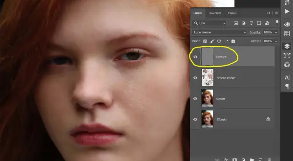 Primo piano di un volto femminile con capelli rossi. Pannello Livelli di Photoshop aperto, evidenziato il livello "texture" per la separazione delle frequenze.