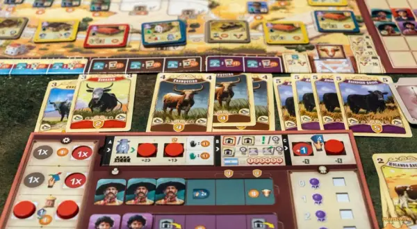 Planszówka Great Western Trail Argentyna z kartami bydła i planszą gracza.