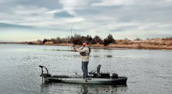 Pescatore su kayak con motore elettrico. Ottimo consiglio batteria motore elettrico per lunghe battute di pesca.