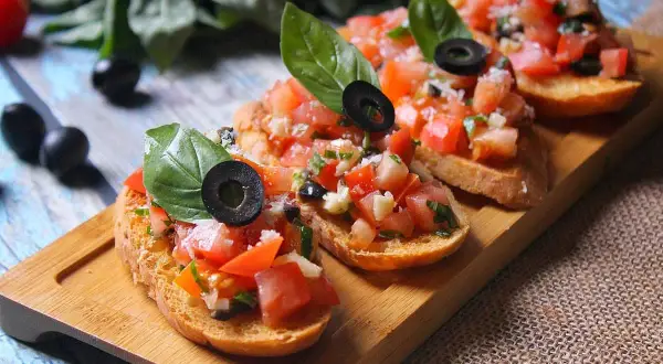 Bruschettas appétissantes avec tomates fraîches, basilic et olives noires sur du pain grillé. Un délice de pain bruschetta.