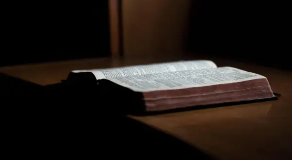 En öppen bibel ligger på ett träbord. Sidorna är fyllda med text, och det ser ut som om det är ett av breven som skrevs Paulus brev till.