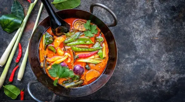 Kolorowe warzywa do curry: groszek cukrowy, papryczki chili, cebula, marchewka i trawa cytrynowa w aromatycznym sosie.