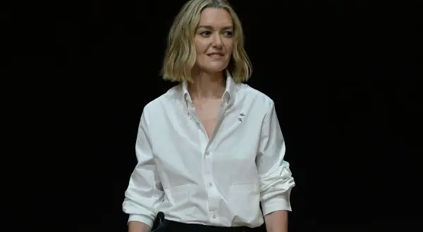 Marta Ortega Pérez, con una camisa blanca y un micrófono, sonríe ante la cámara.