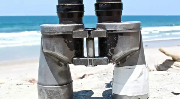 Binocolo sulla spiaggia, pronto a scrutare l'orizzonte. A cosa serve il binocolo? A vedere lontano, a scoprire dettagli nascosti nel paesaggio marino.