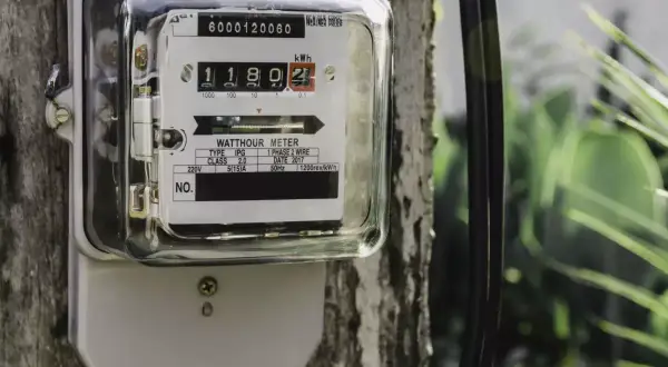 Podłączenie licznika prądu do drewnianego słupa. Urządzenie pokazuje zużycie energii elektrycznej.
