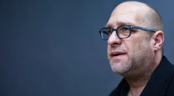 Portret mężczyzny w okularach, łysiejącego, z zarostem. Todd Hido w skupieniu.
