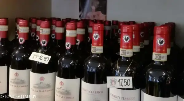 Rzędy butelek wina z kogutem na etykiecie. Na niektórych widnieją ceny: 16,90 i 17,50.