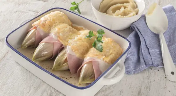 Endives au jambon gratinées, un plat classique dont l'origine est souvent attribuée à Bruxelles. Servi avec une purée onctueuse.